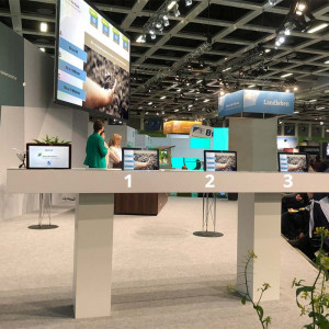 Quiz-Tablets in Theke mit großem Bildschirm als Messe-Display